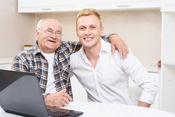 Grandfather and grandson sitting with laptop 