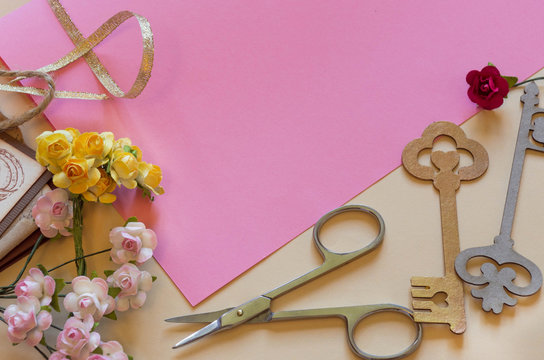 Top view of  paper roses and a pink sheet of paper. Making handm