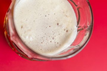 White foam beer close up still on a red background