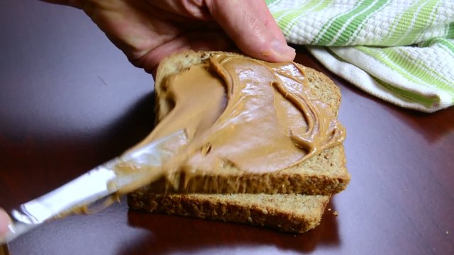 Closeup of spreading peanut butter on wheat bread

