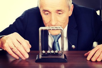 Businessman in office playing with newton balls