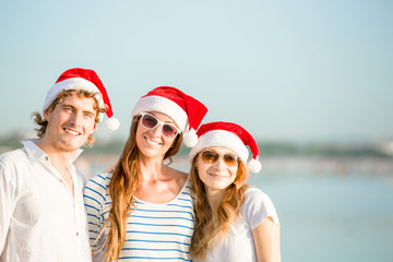 Obraz premium Group of happy young people in christmass hats on the beach