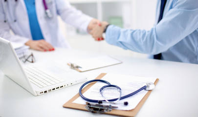 Attractive female doctor shaking a patient's hands in her office