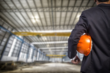 engineer holding orange helmet for workers security on factory b