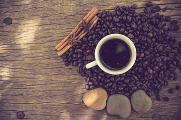 Coffee cup and coffee bean on a wooden table vintage color