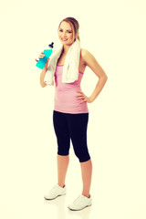 Woman in fitness clothes drinking isotonic drink.