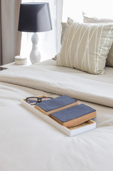 tray of books and glass on bed