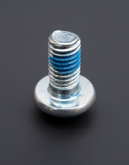 round head bolt with blue loctite on a black background
