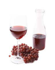 Glass of red wine next to a branch of grapes