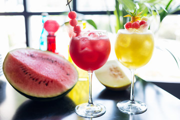 mix of refreshing glass of bright juicy melon and watermalon smoothie or lemonade with ice on a table at a restaurant with the decor of the bright dishes and pieces of melon