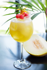 refreshing glass of bright juicy melon smoothie or lemonade with ice on a table at a restaurant with the decor of the bright dishes and pieces of melon