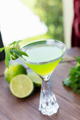 refreshing glass of cold lime lemonade with mint on a wooden table in a restaurant with a creative decoration of mint leaves and fresh lime. soft focus