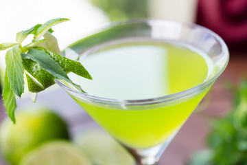 refreshing glass of cold lime lemonade with mint on a wooden table in a restaurant with a creative decoration of mint leaves and fresh lime. soft focus