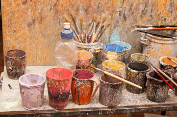 Work table of a pottery decorator of Caltagirone with different color containers and paintbrushes