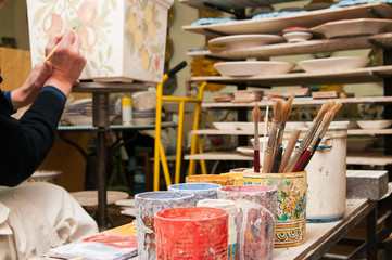 Work table of a pottery decorator of Caltagirone with different color containers and paintbrushes