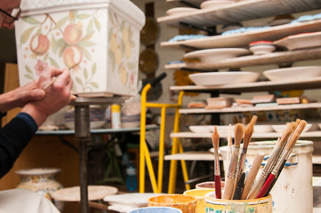 Work table of a pottery decorator of Caltagirone with different color containers and paintbrushes