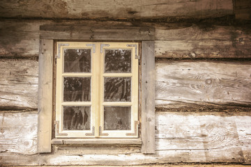 Fototapeta na wymiar Small window in wooden village house cottage.