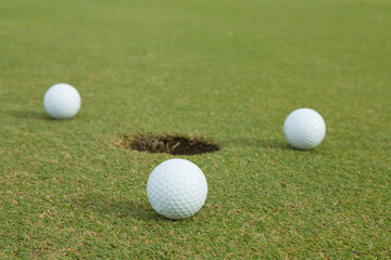 3 golf ball beside hole