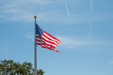 American Flag Blowing on Metal Pole on Blue Sky
