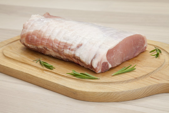 Rollbraten mit Garnierung auf einem Holzbrett, Schweinerollbraten, Karbonadenrollbraten, Holzhintergrund