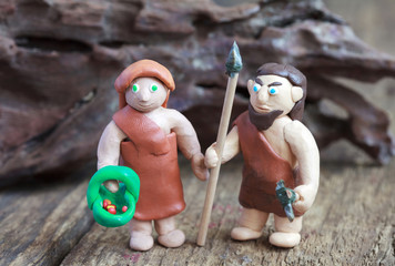 Plasticine world - caveman with spear and stone ax and woman