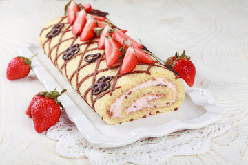Homemade sponge roll with chocolate patterns, strawberries and cottage cheese cream