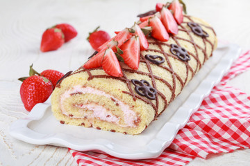 Homemade sponge roll with chocolate patterns, strawberries and cottage cheese cream