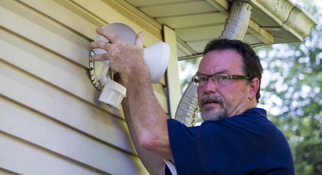 Electrician Putting Up A Motion Detector Light