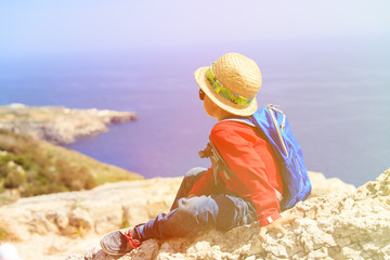 little boy hiking in mountains looking at scenic view