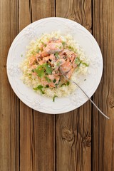 Salmon with rice, scallion and cilantro in white plate on wooden