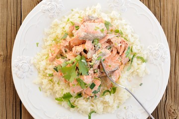 Salmon with rice, scallion and cilantro in white plate with fork