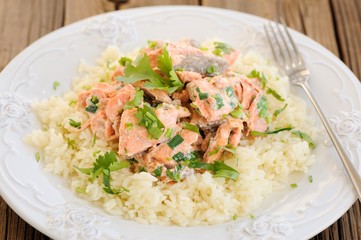 Salmon with rice, scallion and cilantro in white plate with fork