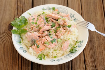 Salmon with rice, scallion and cilantro in white plate with fork