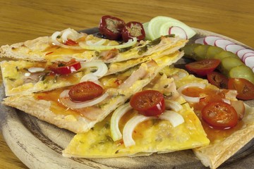 Homemade pizza, sliced on a wooden chopping boards, flavored with chilli peppers. Detail view.
