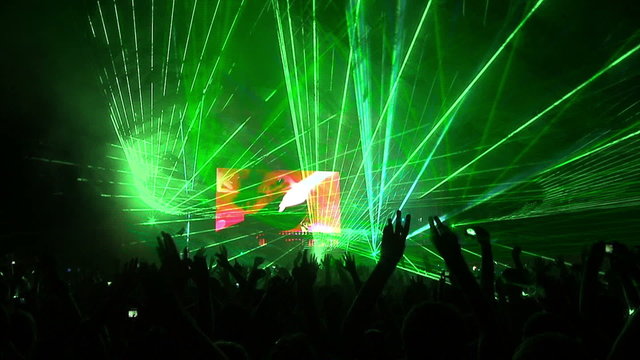Dancing people partying at a concert with night laser light show