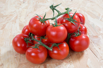 Fresh  tomatoes on a cluster over wooden  table
