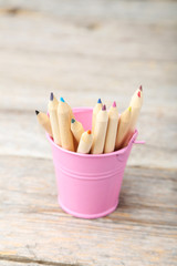 Colorful pencils in bucket on grey wooden background