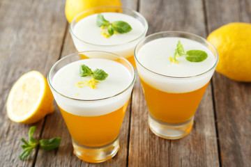 Tasty lemon jelly in glass on grey wooden background