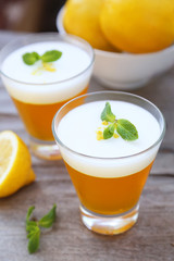 Tasty lemon jelly in glass on grey wooden background