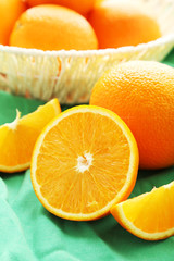 Ripe oranges in basket on green background