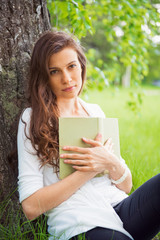 Fototapeta premium Portrait of spring brunette girl seating outdoor at the tree wit