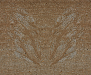 Silhouette of butterfly wings made of sand and gravel by water flow at concrete surface