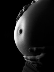 Barriga de embarazada sobre fondo negro - obrazy, fototapety, plakaty