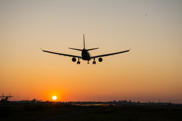 Plane is landing during sunrise.