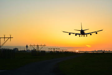 Fototapeta na wymiar Plane is landing during sunrise.