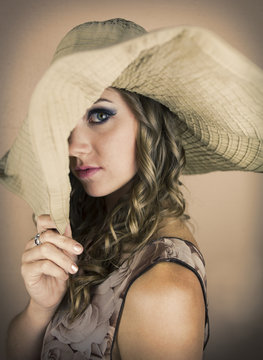 Pretty young woman with big hat pulled over one eye.