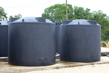 Water tanks holding rain water sit on a concrete slab. 