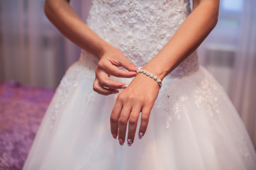 Obraz na płótnie Canvas Bridal preparation, bride putting on jewelry, focus on bracelet