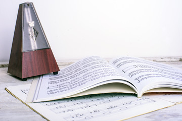 metronome and music notes on white vintage wooden background