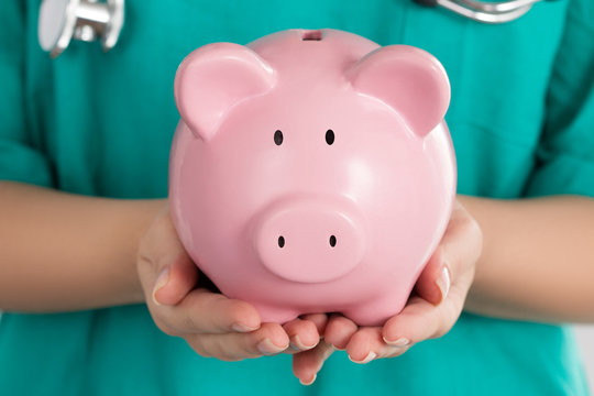 Female Doctor Holding Piggy Bank